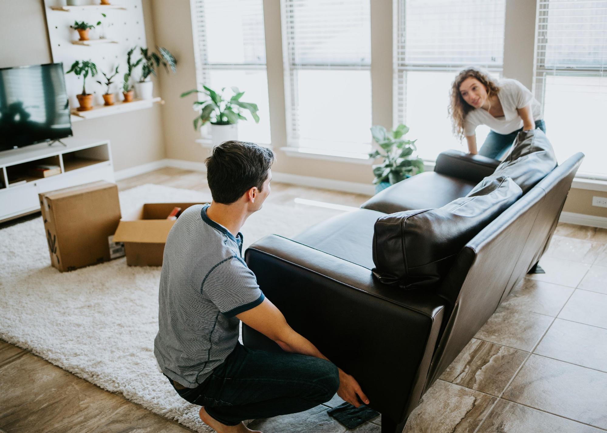 Young couple moving a couch inside.