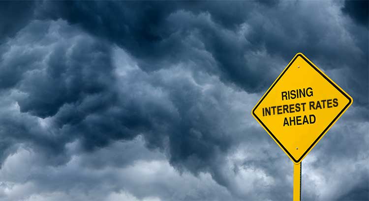 caution sign that reads Rising Interest rates ahead, storm clouds in background