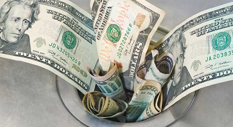 american money bills going down a garbage disposal