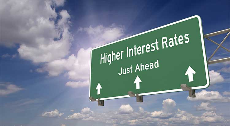 highway sign pointing to higher interest rates, blue sky white clouds