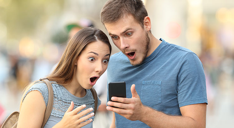 male and female looking surprised at something on a phone screen