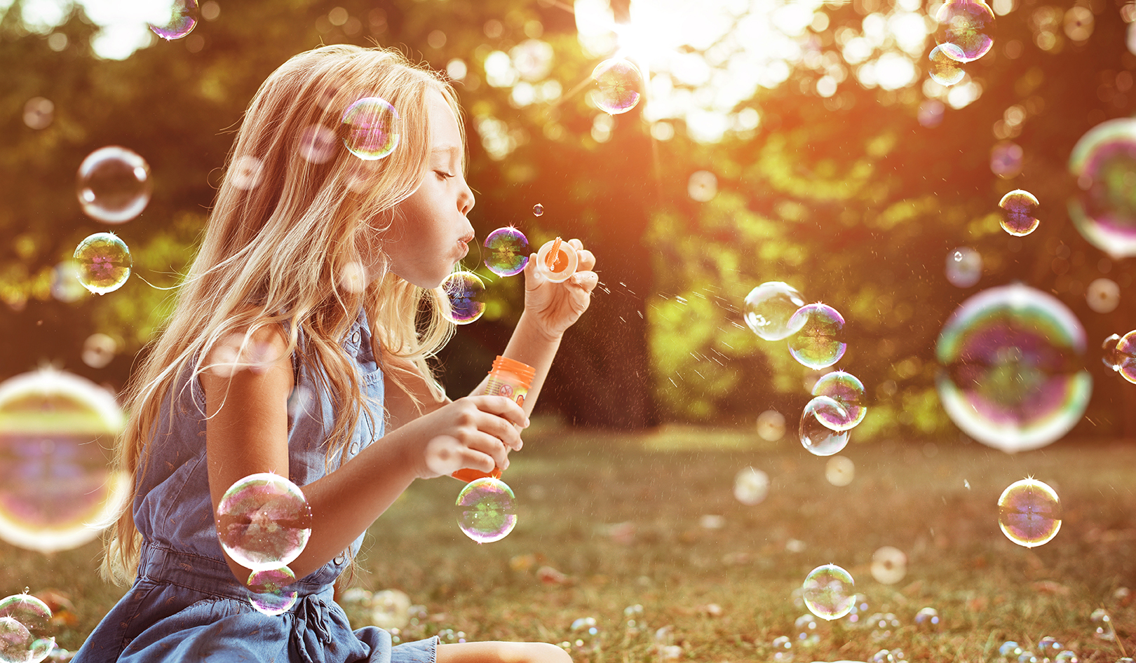 little girl blows bubbles outside