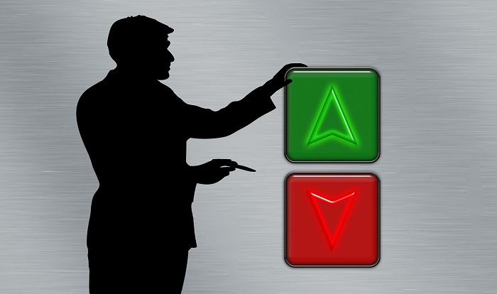 silhouette of a man pointing at elevator buttons one green arrow up othe red arrow down 