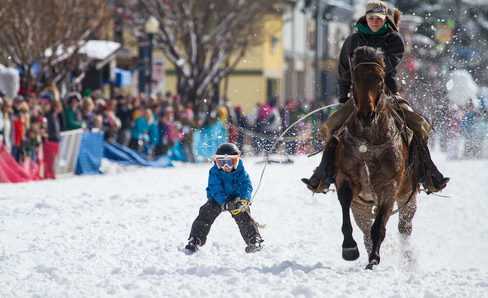 Kid Racing on Skis Behind a Woman on a Horse at the Steamboat Springs Winter Carnival
