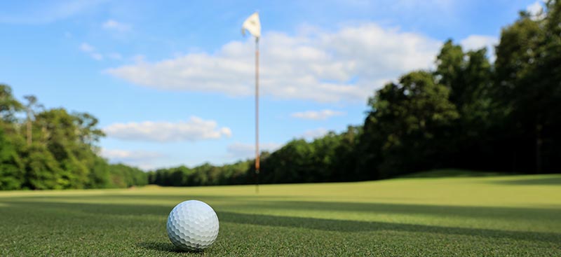 Golf ball and flag on golf course
