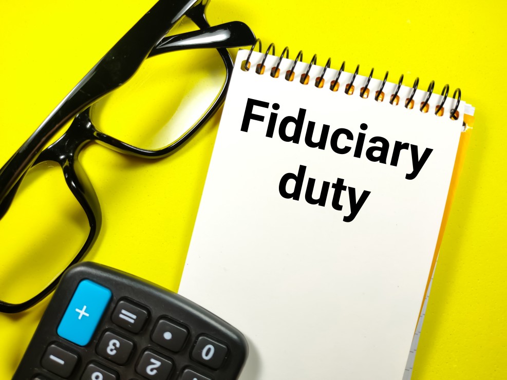 Eye glasses with a calculator and note pad that states fiduciary duty on a yellow background