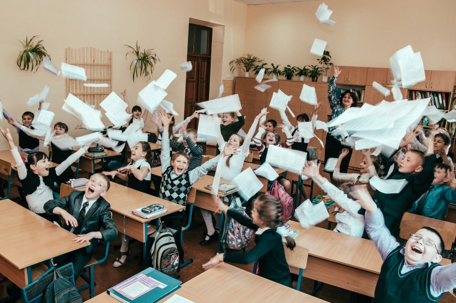 Charleston school kids celebrating by throwing papers into the air while sitting at their desks