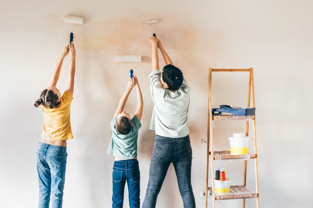 Three women of all ages painting a wall in their Charleston home