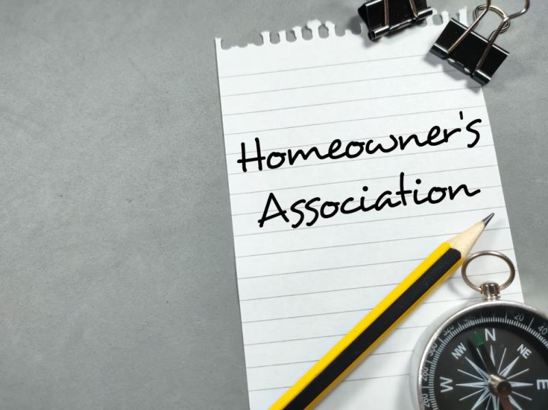 Home Owners Association text written on lined white paper torn from spiral notebook with a pencil and compass