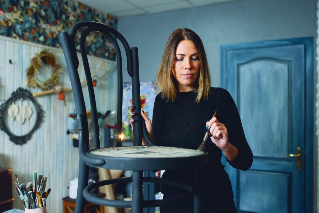 creative designer restoring and painting an antique chair