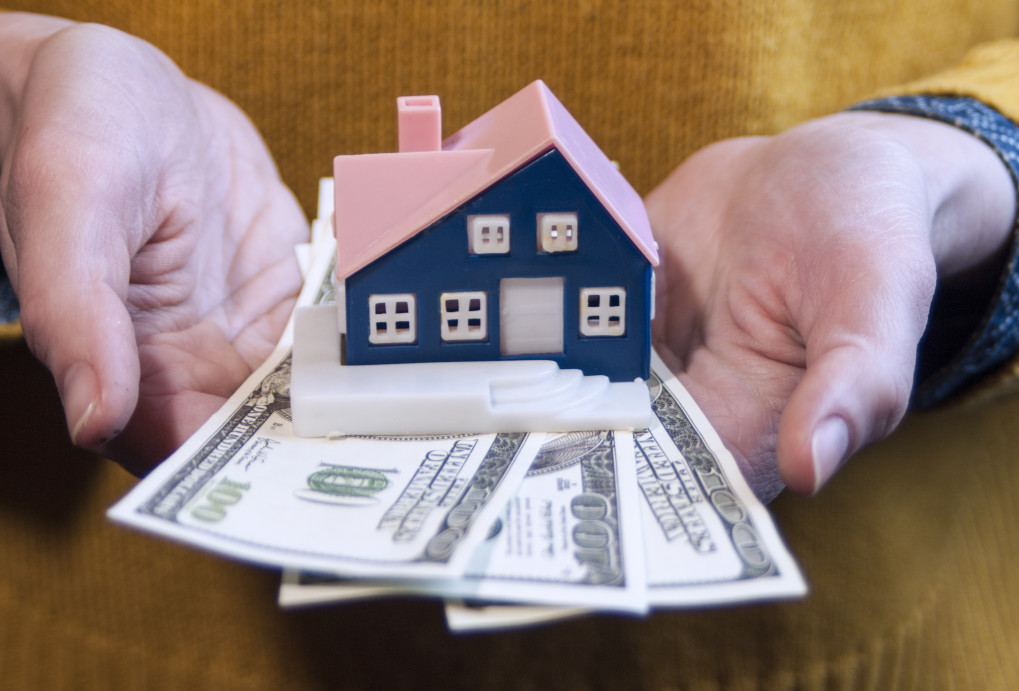 Woman holding model of Charleston South Carolina Home with Cash Underneath