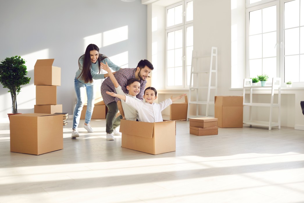 family-with-children-having-fun-in-new-home-joyful-first-time-buyers-with-kids-playing-with-boxes-