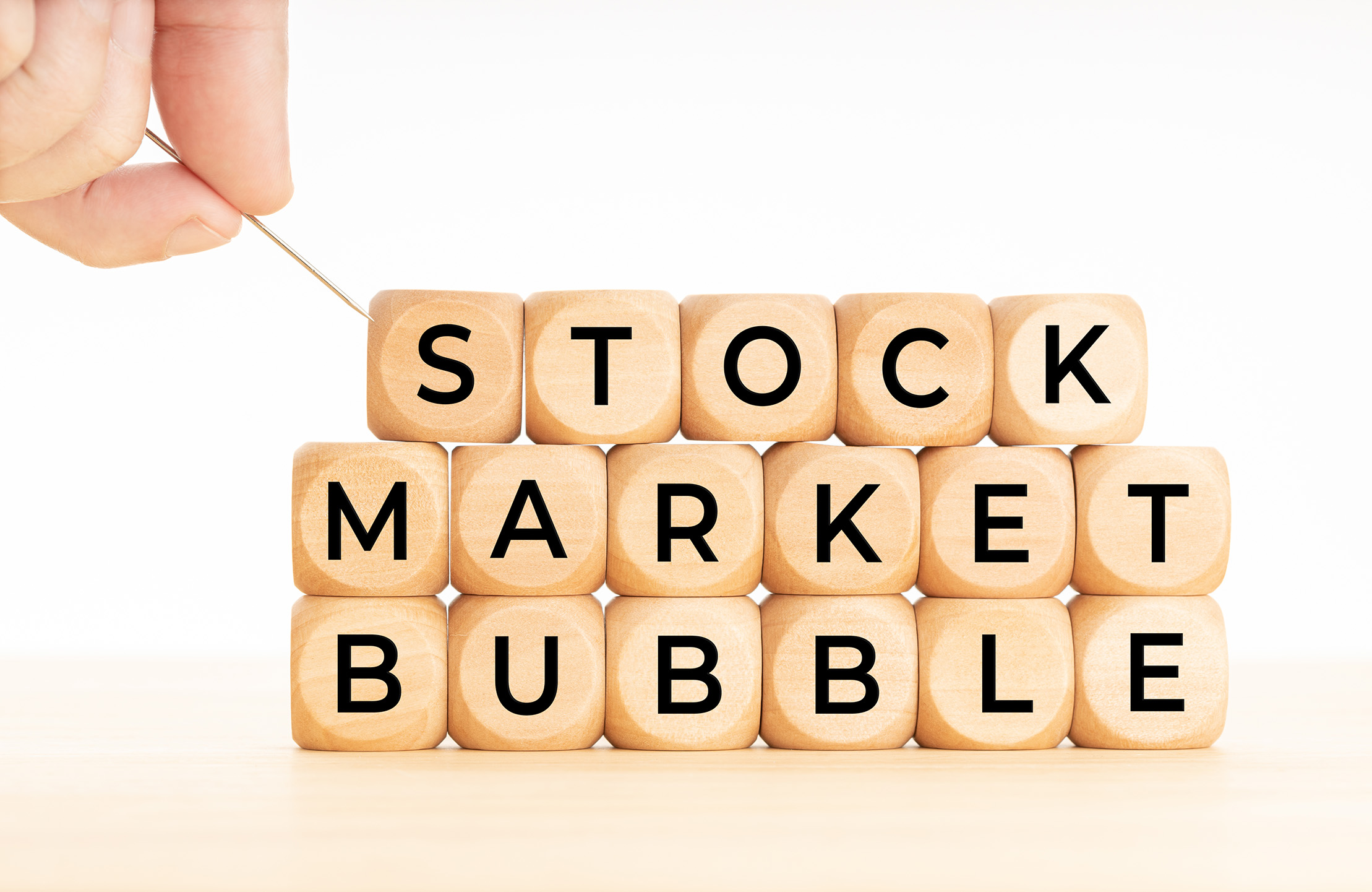 Person Holding a Pin above Stock Market Bubble Text written in Blocks