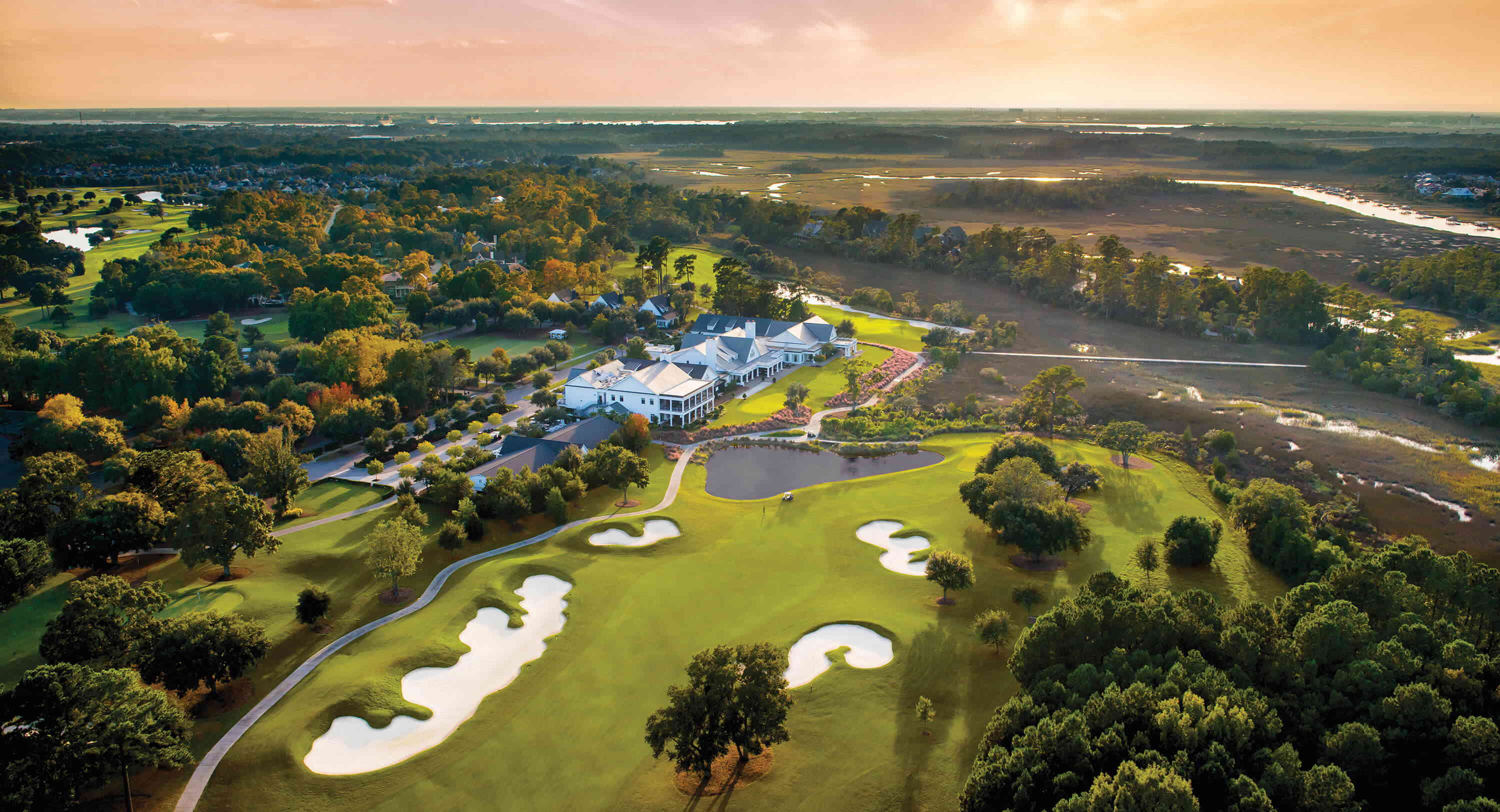 aerial view of Daniel island south carolina golf course with homes and wetlands in the background at Sunset