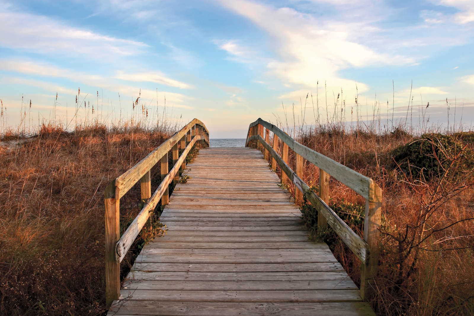 Sullivans Island Home Wooden Walkway between two sand dunes leading to the beach at sunset