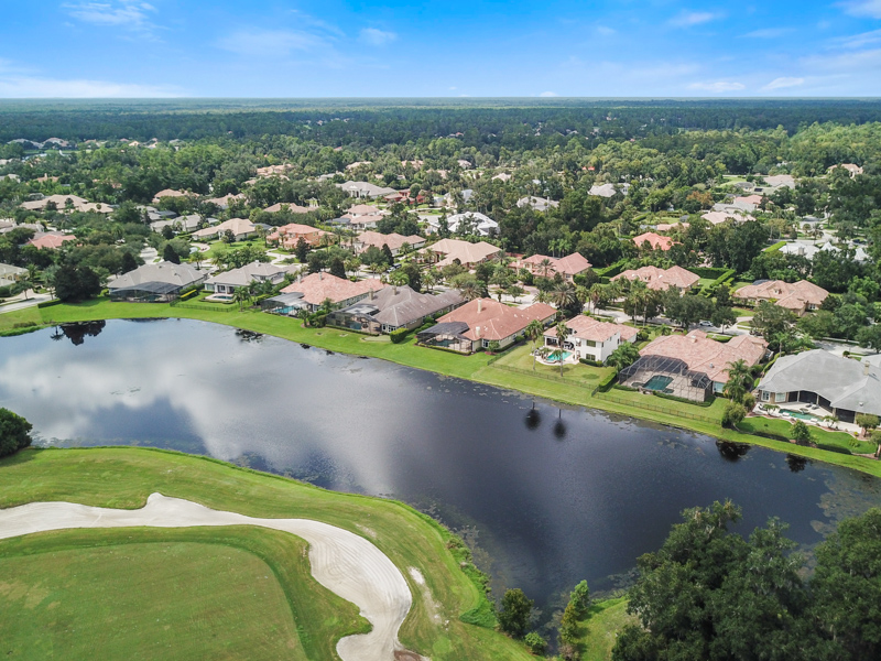 An drone view of a neighborhood in Alaqua Lake Florida located on a pond within a beautiful golf course community. 