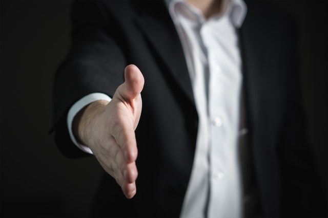 a real estate agent offering a handshake to buy and sell a home at the same time