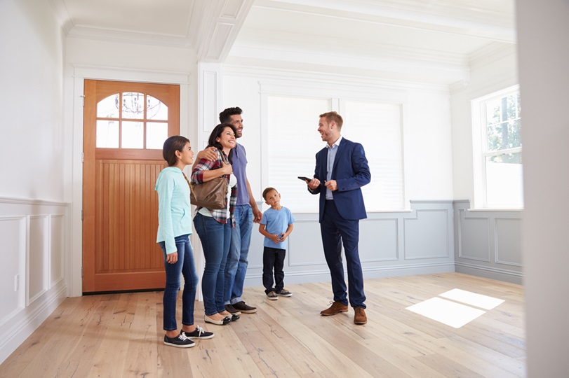 Real Estate agent with clients consiting of parents, teenage daughter, and boy. All standing in an updated house, by the front door