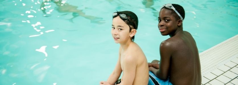 Two boys sitting in front of a pool looking back 