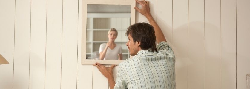Hanging up a mirror against a white wall 