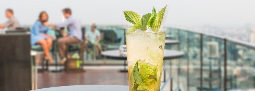 A drink sitting on a table at a rooftop bar 