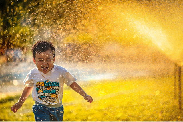 boy playing in sprinkler