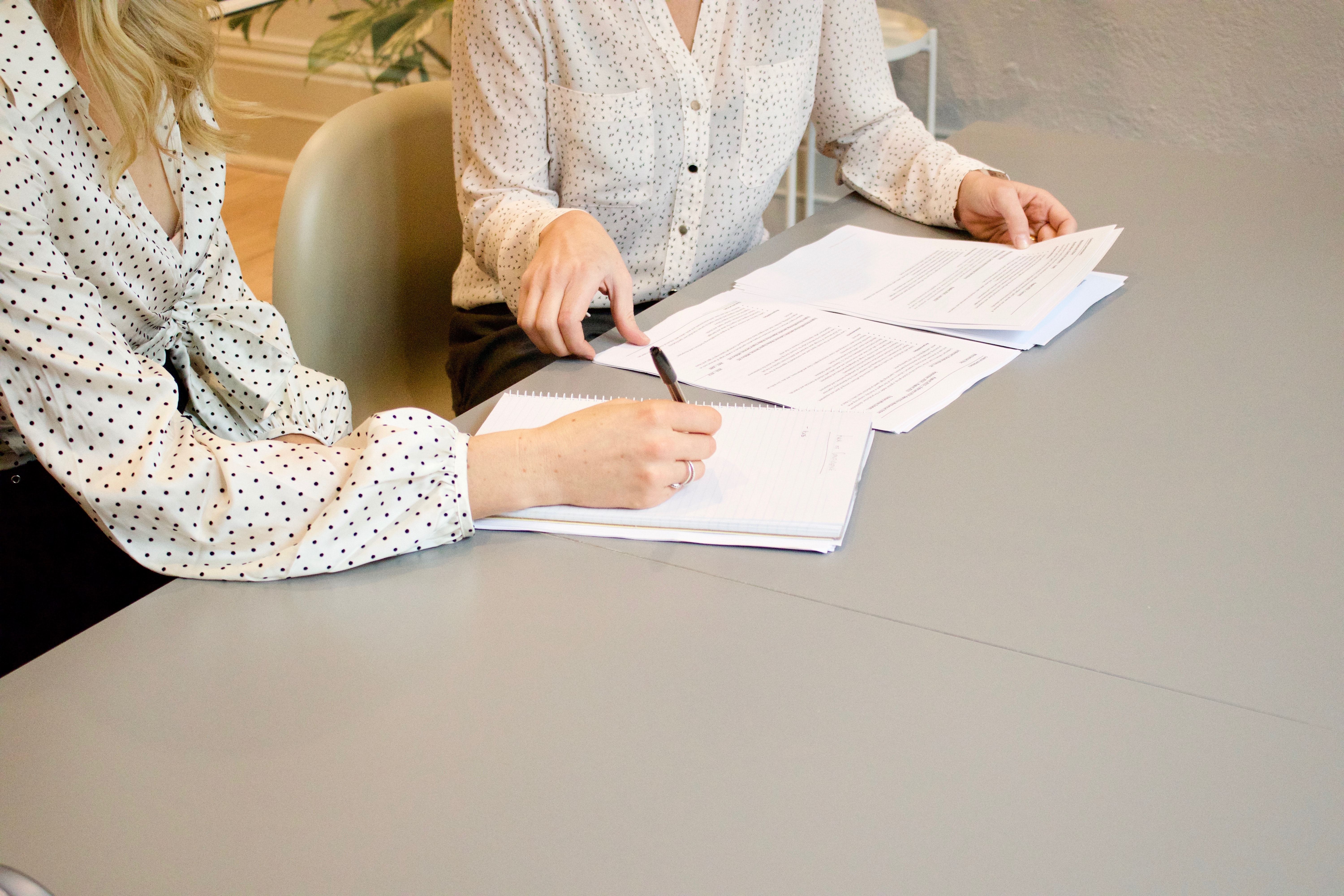 Two women having a meeting at a table with documents on it.