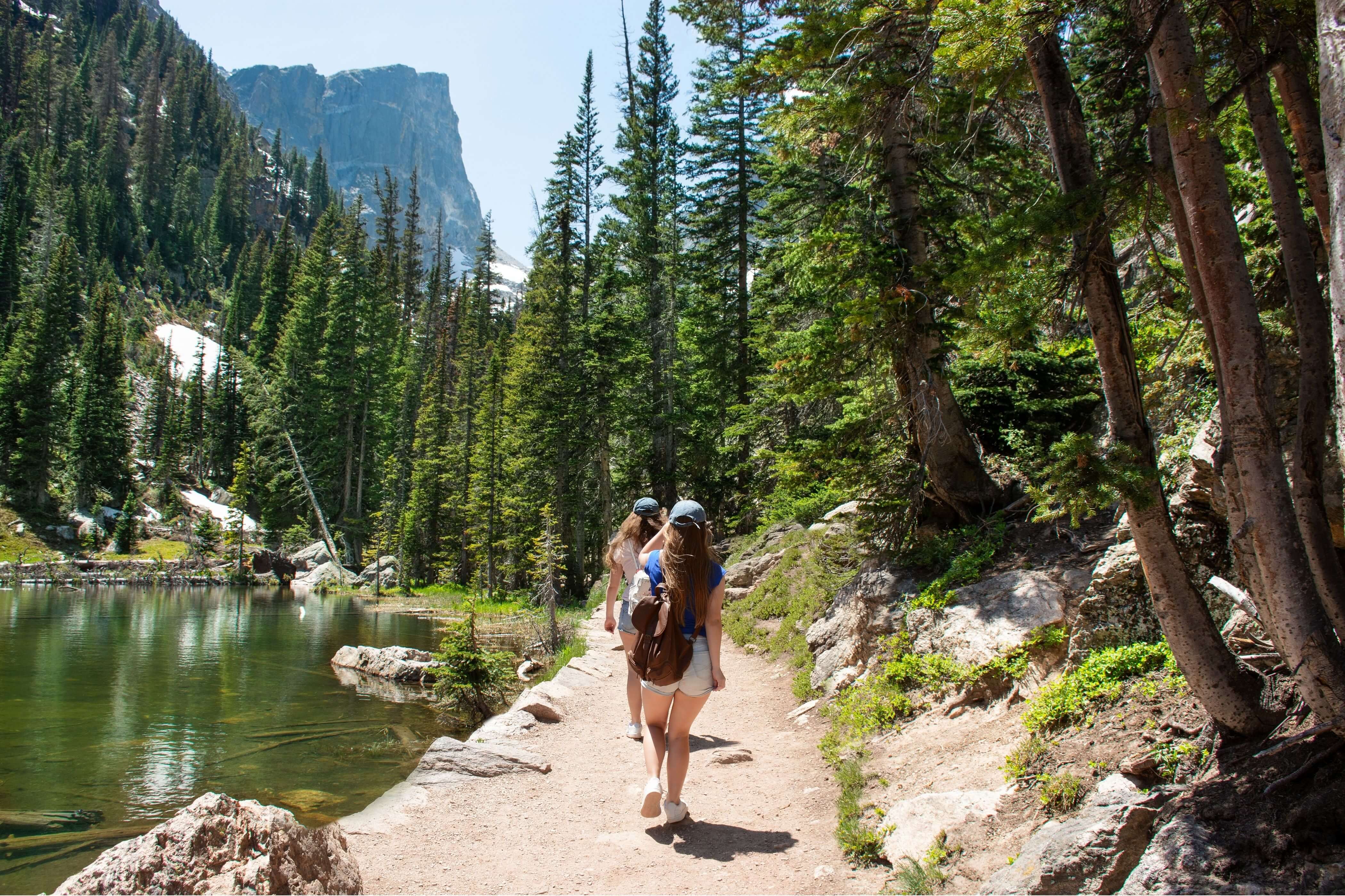 Two women hiking in Colorado next to an alpine lake in the mountains.