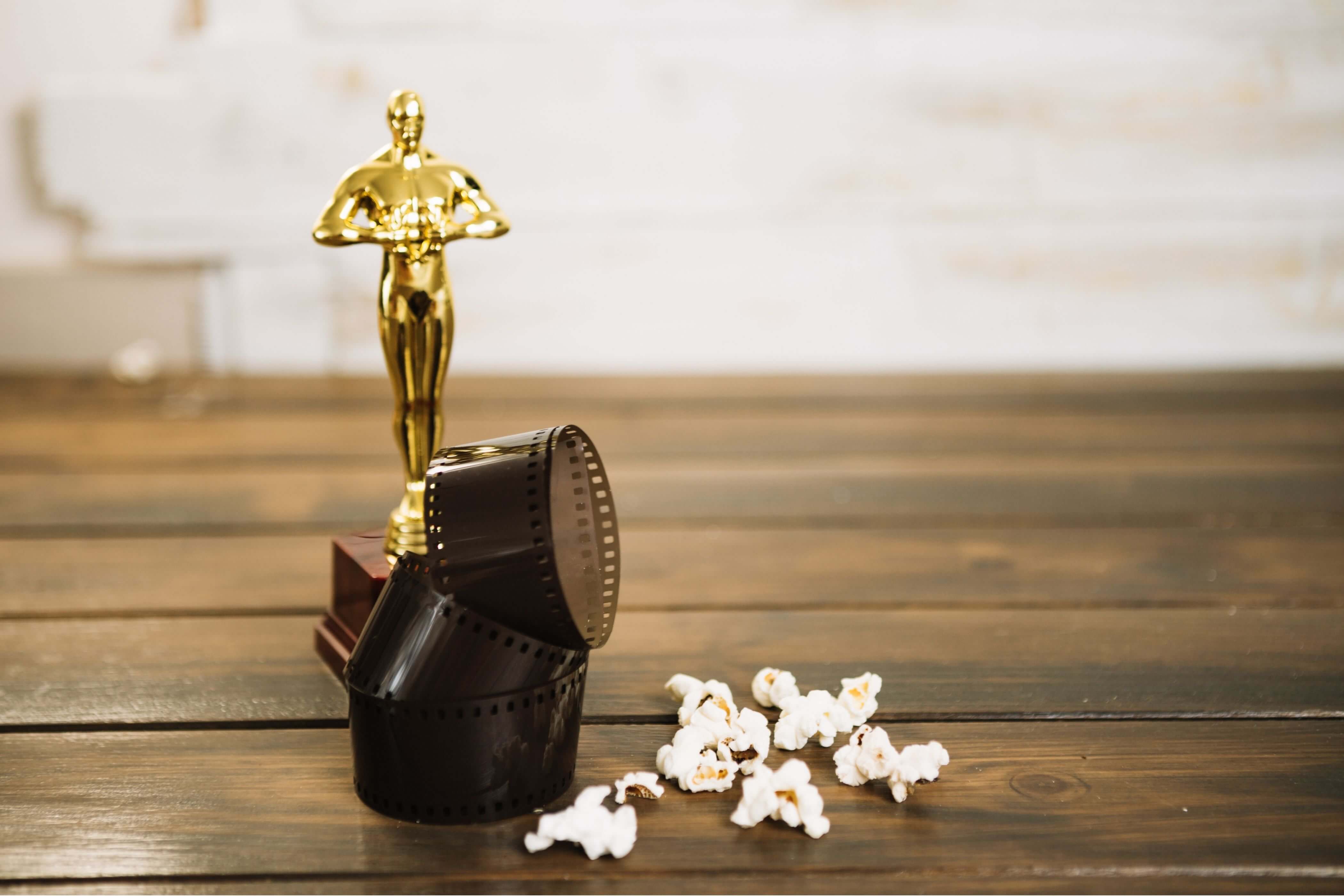 An Oscar movie award with a film reel and spilled popcorn.