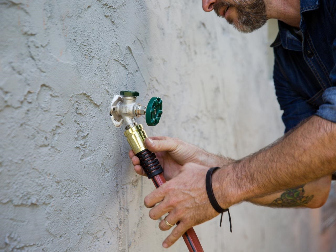 A person disconnecting a garden hose