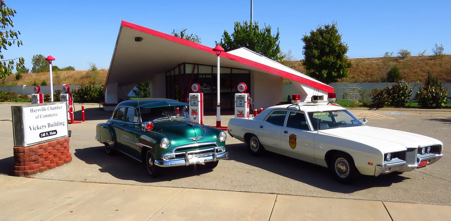 Classic cars sit outside of a unique-looking petroleum service station