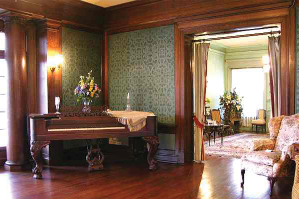 Image of one of the living spaces with a piano inside the Brown Mansion