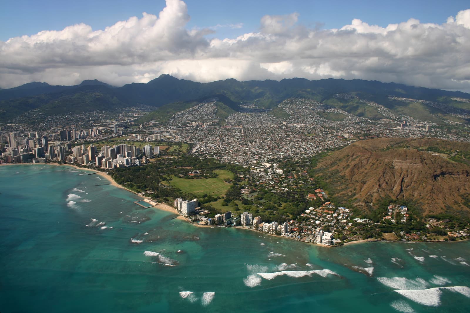A strip of land with condos near the shoreline along the southern shore of Oahu, shot from above