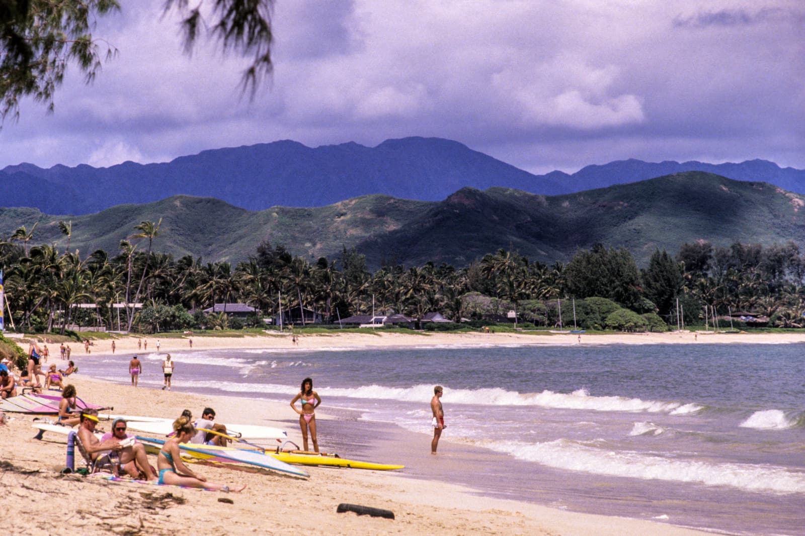 A picture of a public beach on Oahu, showing people along the beach and in the ocean