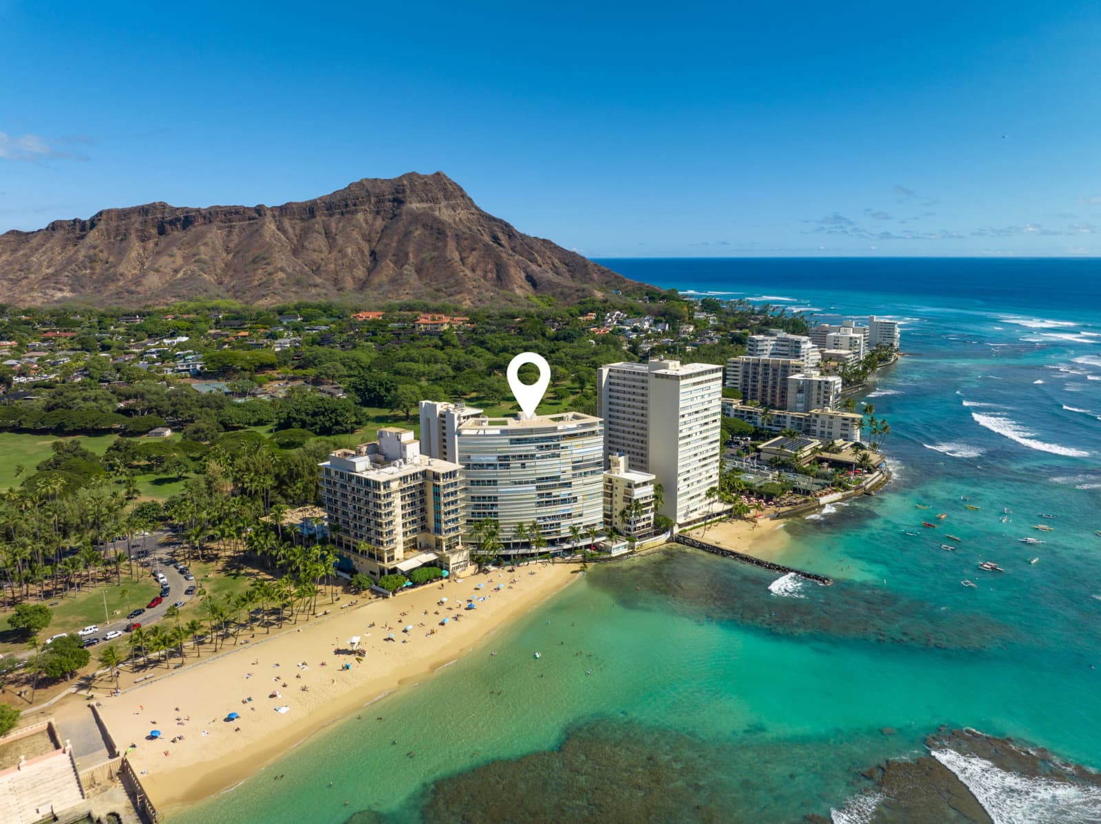Aerial shot over the Gold Coast of Oahu with a marker over the Sans Souci condominium facing toward the island