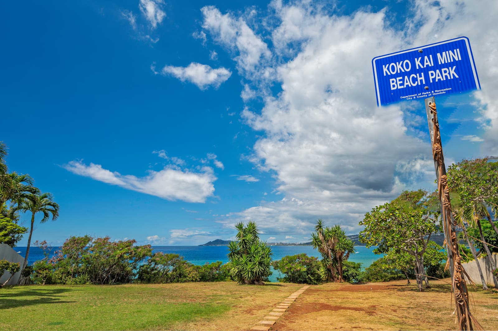 Sign that says Koko Kai Mini Beach Park overlooking grass, trees, and the ocean beyond