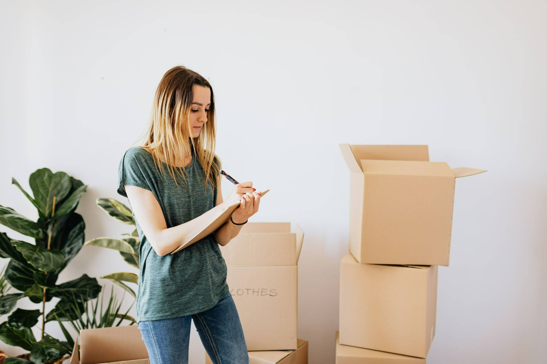 A woman writing down notes while packing.