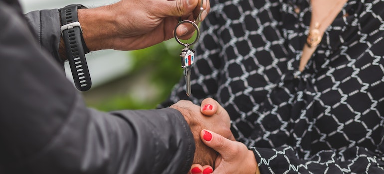 A person handing over a silver key.