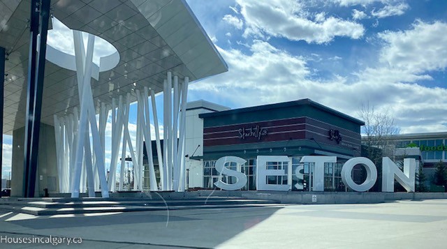 A large sign with "Seton" on it in Calgary. There is a restaurant with "Starbelly" in the background and white art poles and steps in the front.