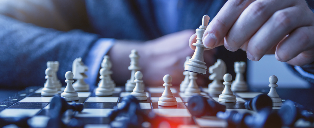 Close up image of a chess board with a person in a suit sitting behind it out of focus