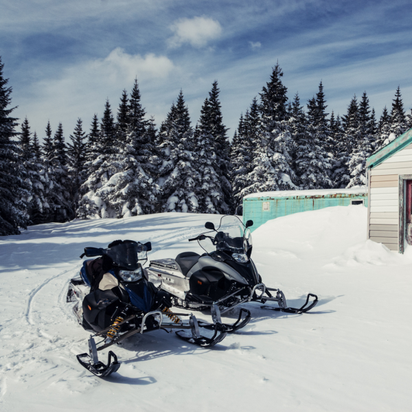Two snowmobiles by building
