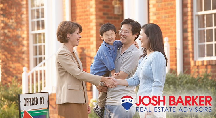 Real estate agent with a couple and their kid, everyone smiling and shaking hands.