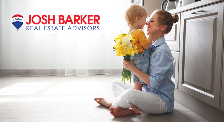 Woman sitting on the floor with her son between her arms and holding flowers in her left hand
