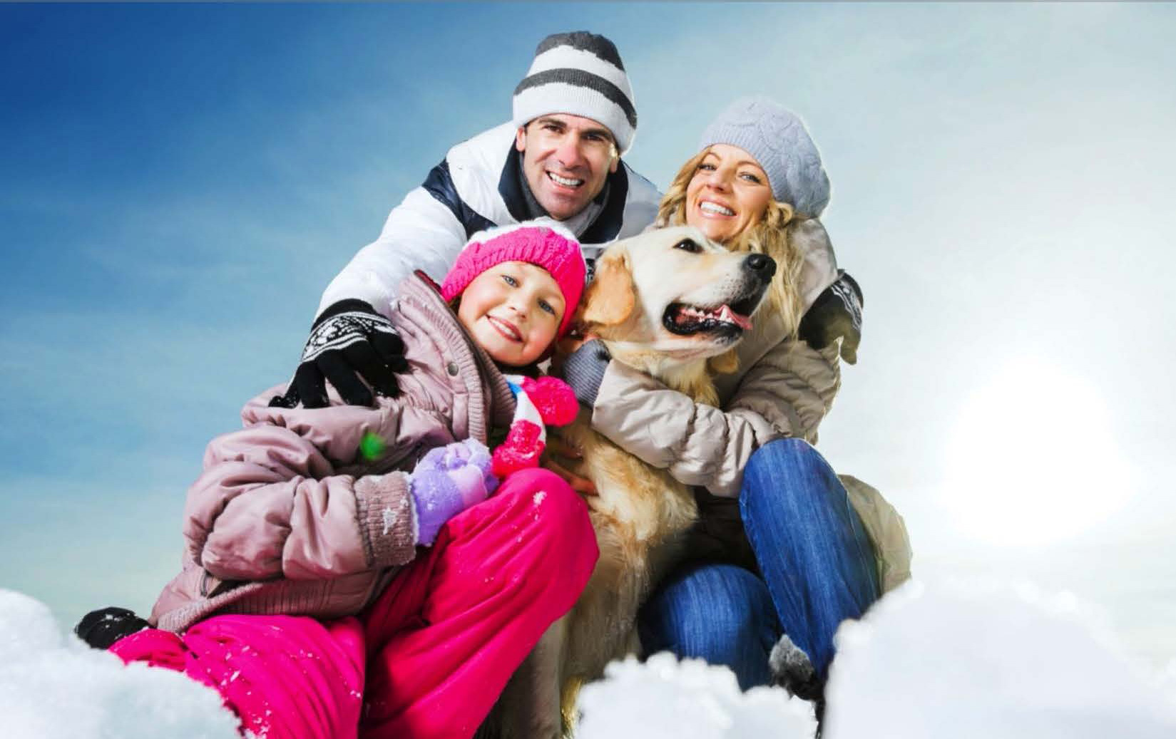 Happy family with their dog in the snow