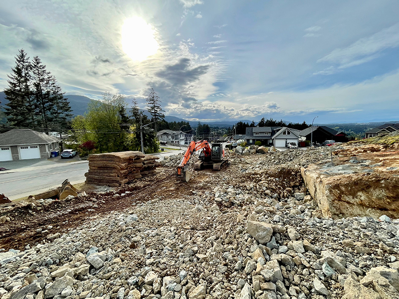 Excavator removing blast rock from new building lot