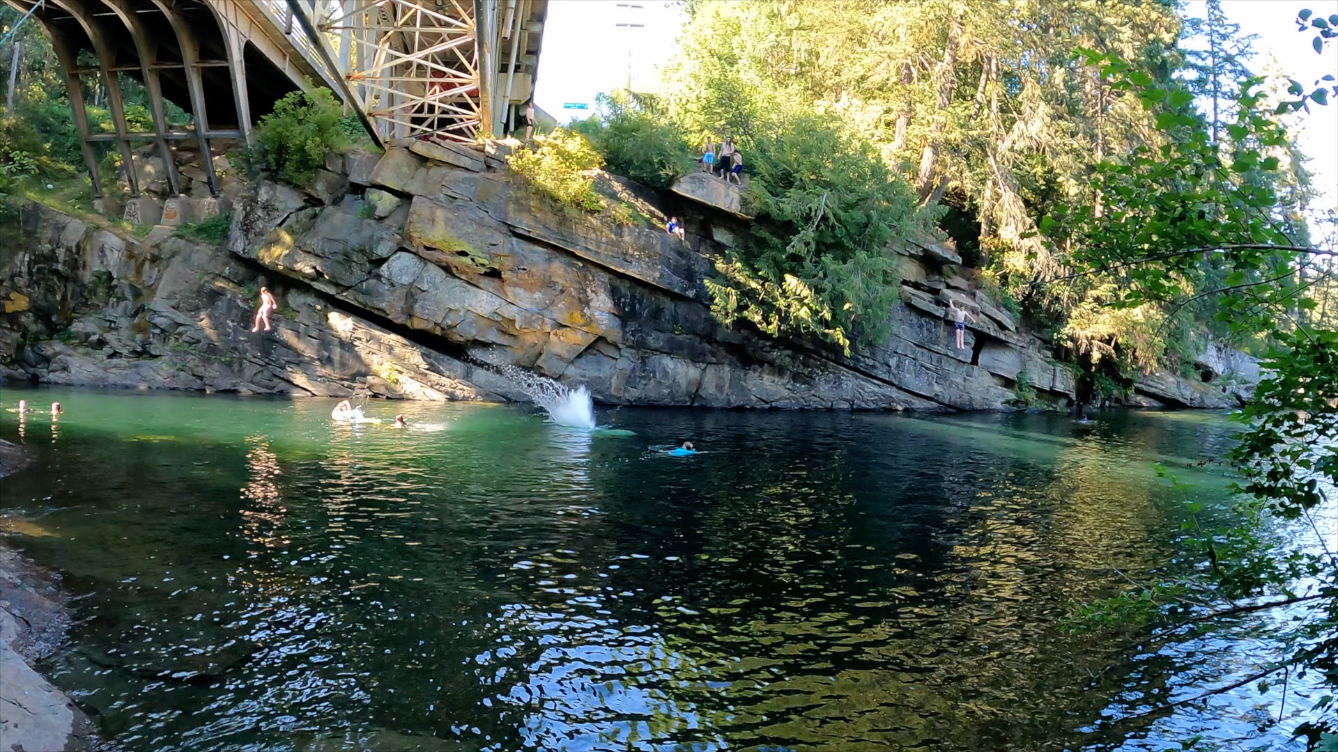 People jumping off cliffs into the Nanaimo River under a Trestle Bridge