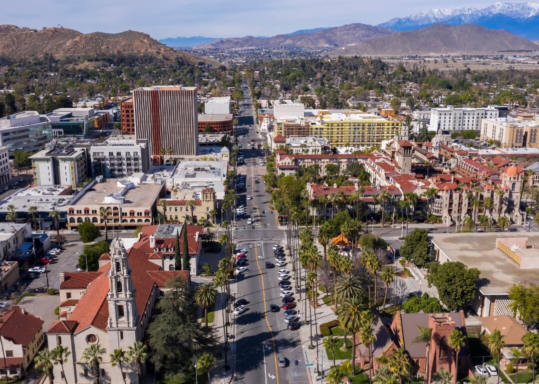 #5. Riverside, California An aerial view of Riverside, California, downtown covered in palm trees and terra cotta rooftops with a mountainous backdrop