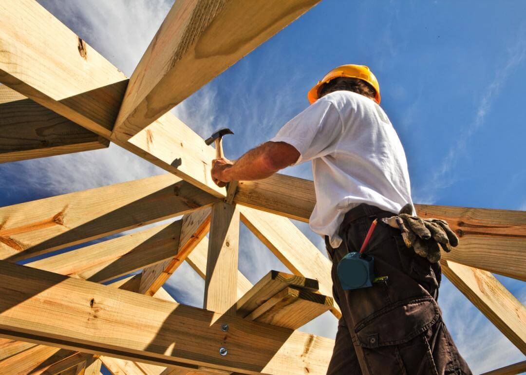 Carpenter working on roof structure on construction site.