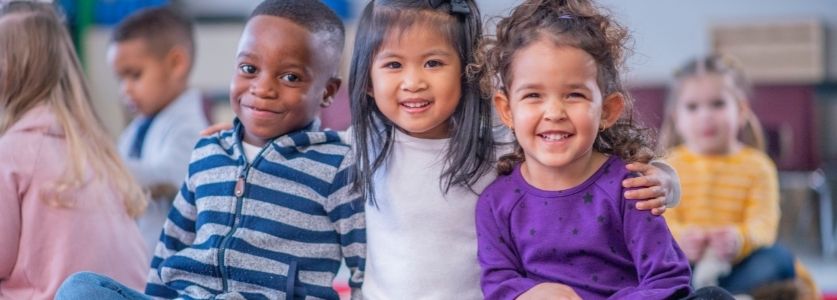 3 multicultural kids smiling at daycare
