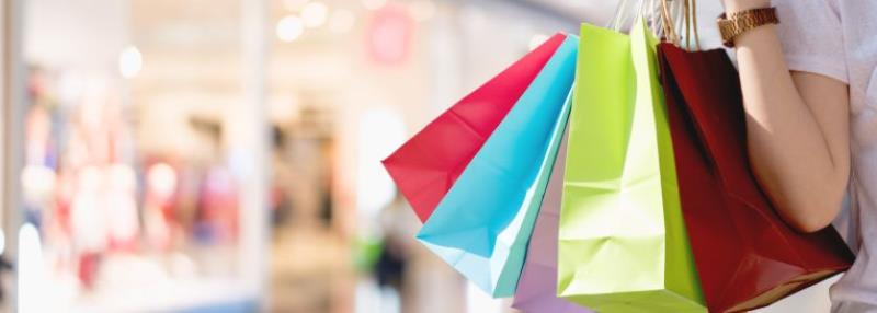 female hand clutching several multicolored shopping bags
